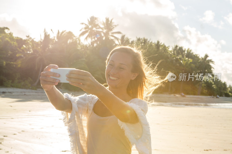 金发女孩用手机在海滩上自拍