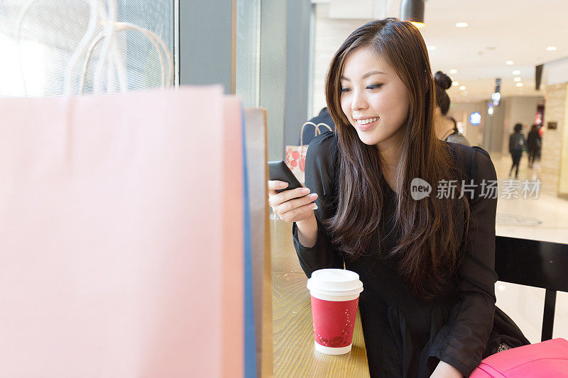 年轻的亚洲女人在现代购物中心购物