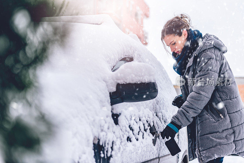 女人打开被雪覆盖的汽车