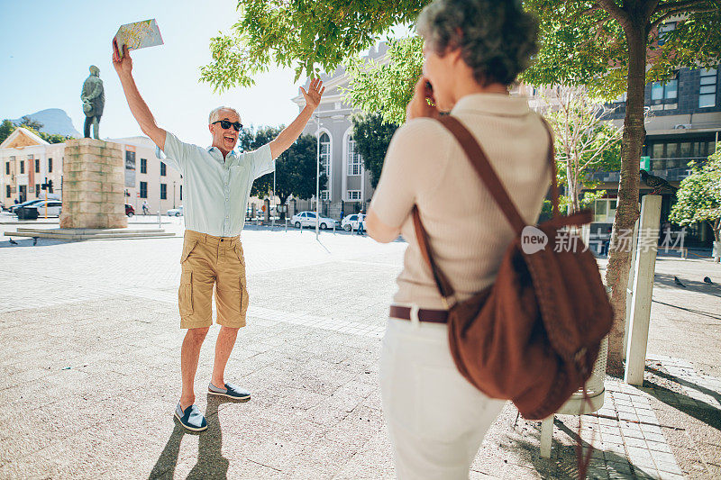 一名女子正在为一位兴奋的年长男子拍照
