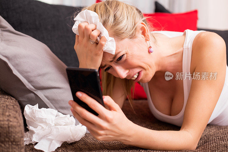 一个手里拿着手机躺在沙发上哭的女人