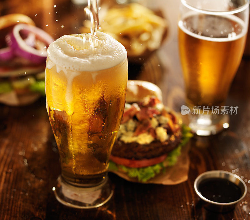 啤酒和美味汉堡一起倒进玻璃杯里