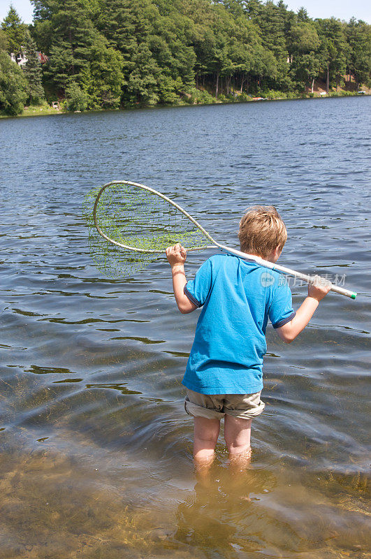 带着渔网在湖中涉水的小男孩