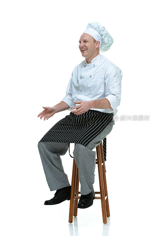坐在凳子上微笑的厨师看着别处