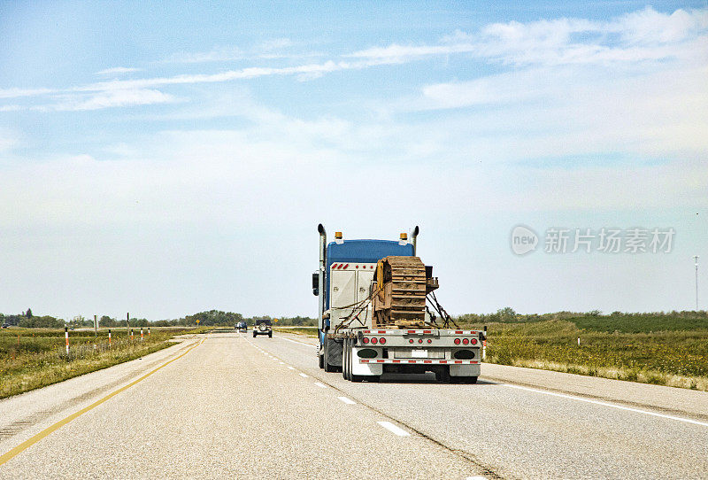 运输推土机在平板卡车上沿着高速公路行驶