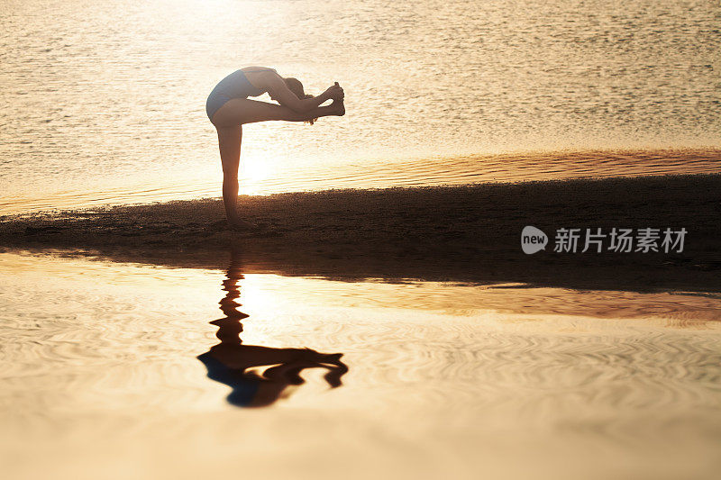 日落时在海滩上做瑜伽的女人