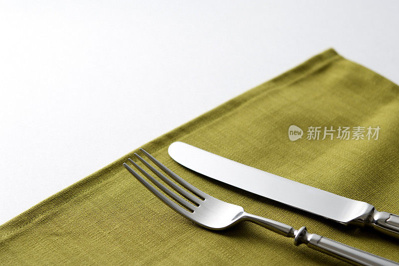 白色背景上的绿色餐巾和刀叉