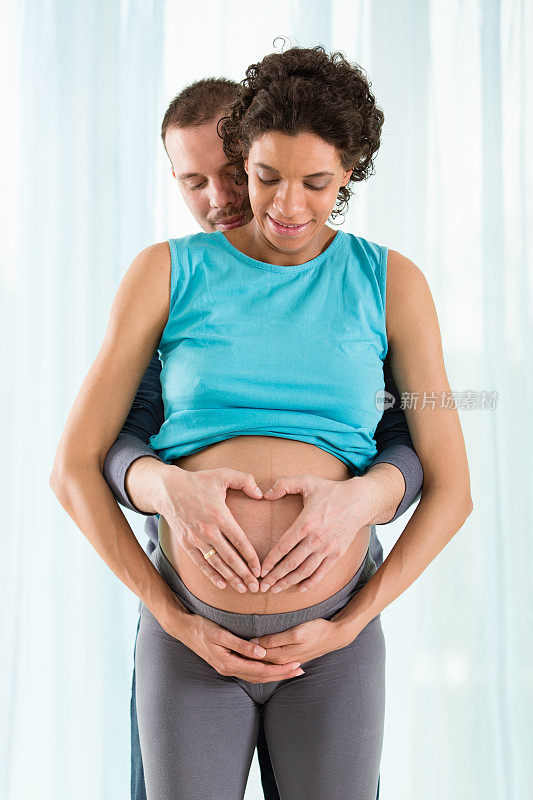 一对怀孕夫妇用手做心形