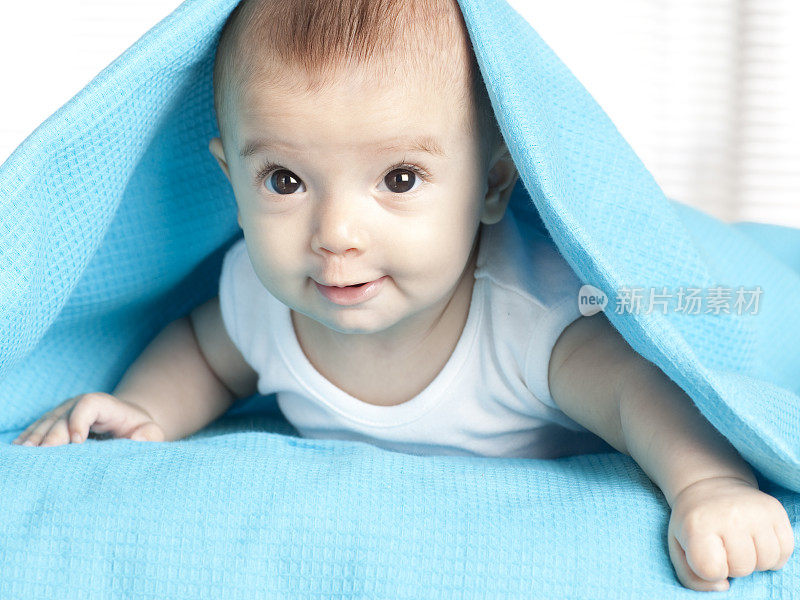 蓝色毯子下面的婴儿。