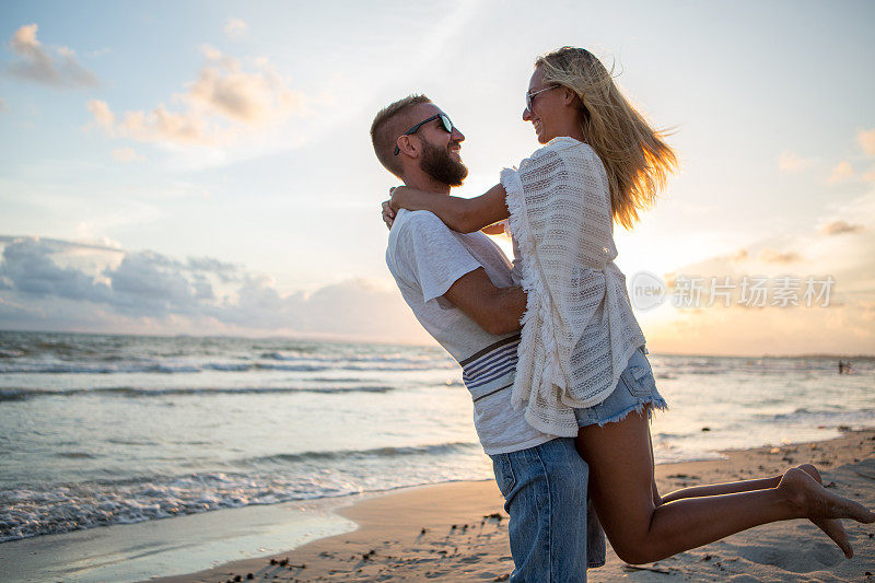 日落时分，一对年轻可爱的夫妇在海滩上热情洋溢