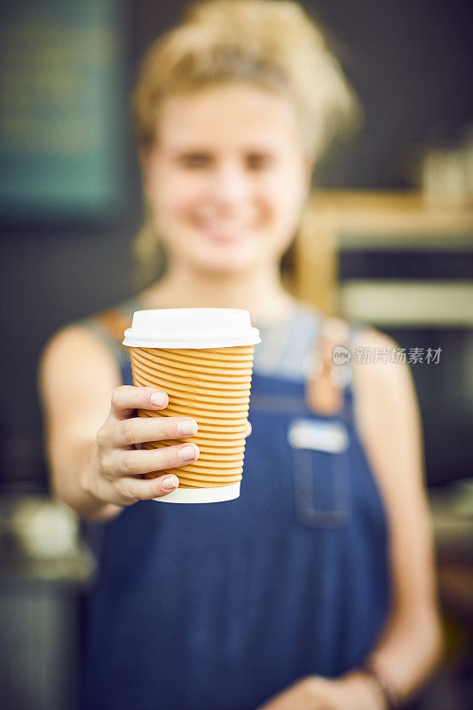 年轻的咖啡师提供一次性咖啡杯