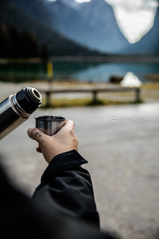 在山中端着一杯热咖啡的男人