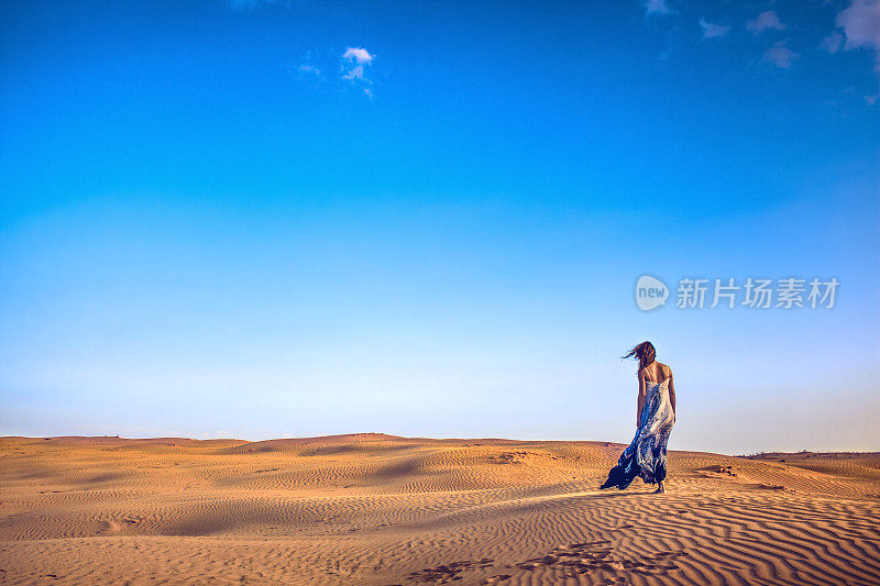 苗条的女孩站在沙丘上