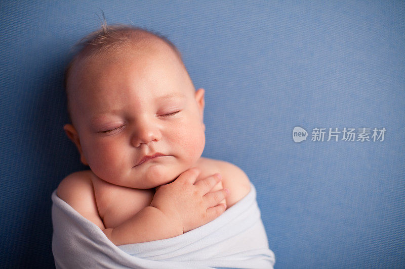 婴儿安静地睡在蓝色背景，与复制空间