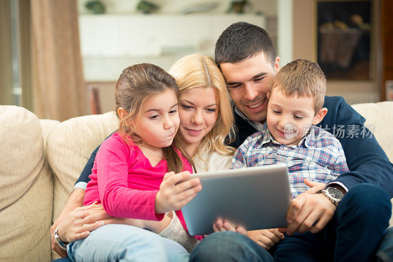 快乐的家庭玩数字平板电脑的肖像