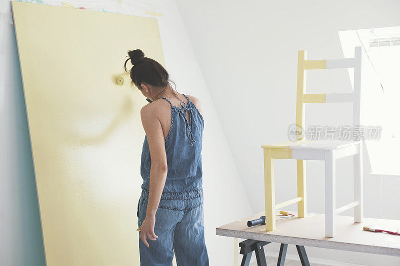 女人在用黄色油漆油漆墙