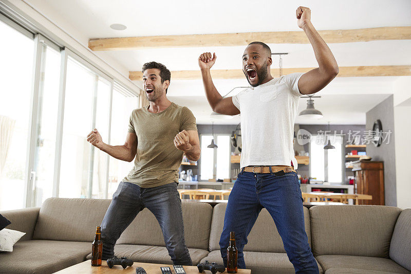 两个兴奋的男性朋友庆祝看电视体育节目