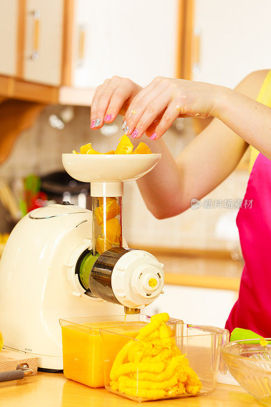 在榨汁机里榨橙汁的女人