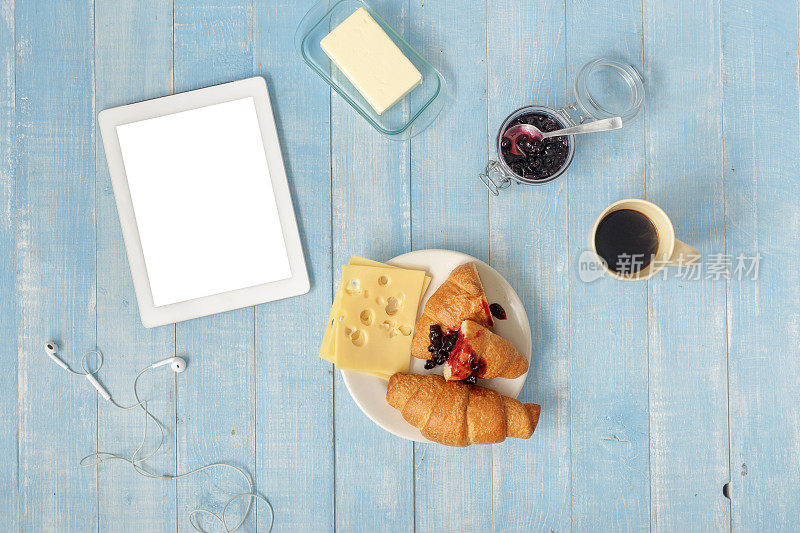 家庭厨房里的俯视图早餐桌有白色药片、咖啡、羊角面包、奶酪和果酱