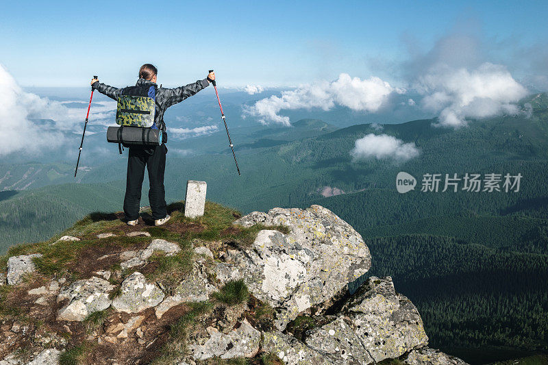 徒步旅行者站在山顶上，欣赏着山脉的景色