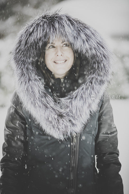年轻漂亮的女子在暴风雪中穿着皮大衣