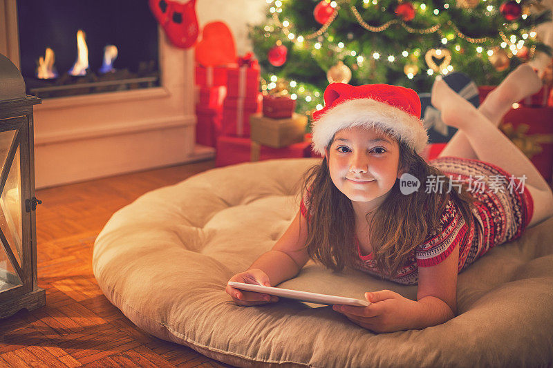 美丽的小女孩在圣诞节晚上使用数码平板电脑