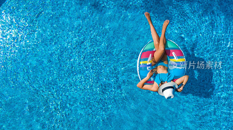 鸟瞰图美丽的女孩在游泳池从上面，游泳在充气圈甜甜圈和有乐趣的水在家庭度假