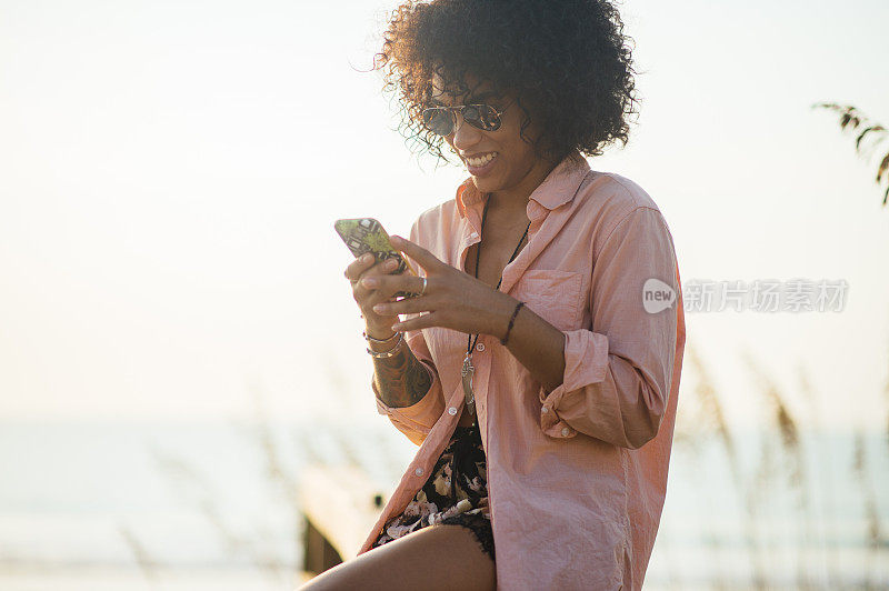 千禧年黑人女性在海滩上用手机