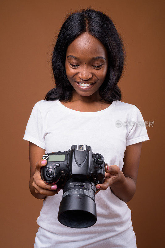 工作室拍摄的年轻美丽的非洲祖鲁妇女拿着数码相机准备在彩色背景下做短视频