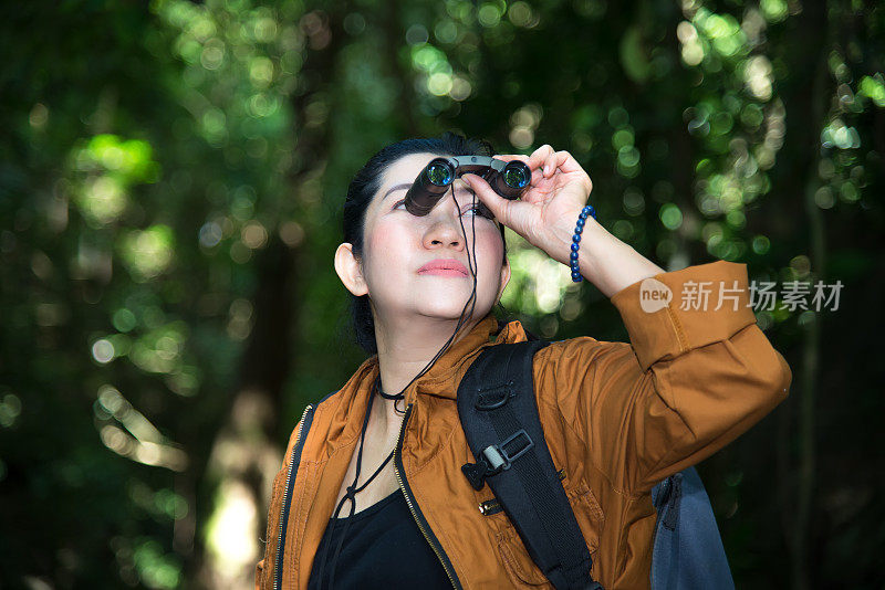 女游客在森林里看望远镜。旅行的概念。