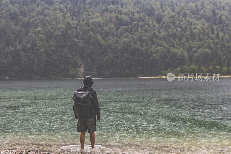 一个徒步旅行者冒雨走进湖中休息他的脚