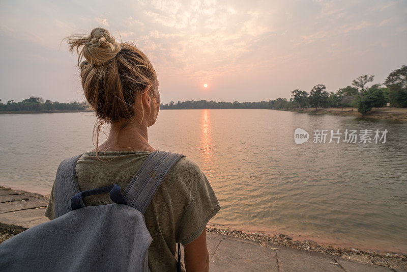 年轻女子凝视日落在柬埔寨的湖边