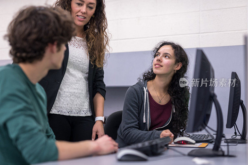 民族技术教师在计算机实验室帮助一个学生