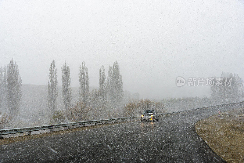 路面有雪，左侧有保护杆，右侧有急转弯，车朝相反方向行驶