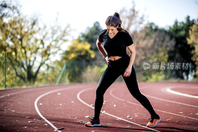 美丽的运动运动女人伸展在运动轨道上