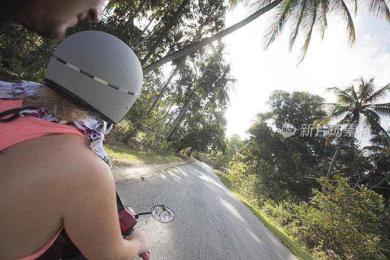 年轻的成年夫妇在摩托车上探索热带岛屿
