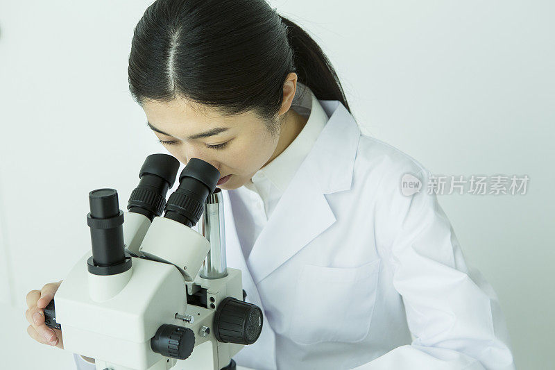 在显微镜下观察的中年女性研究员