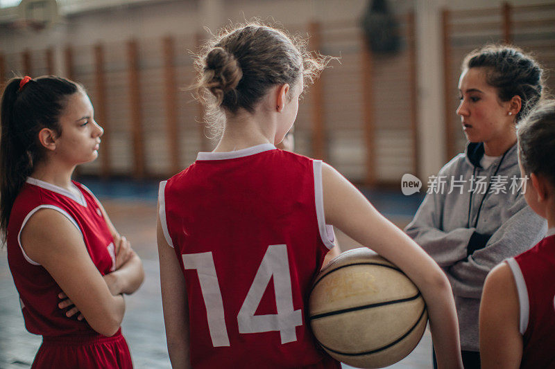 年轻女孩和她们的篮球教练在室内训练