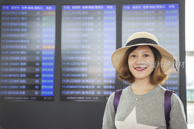 美丽的亚洲女性旅行者在航班信息屏幕