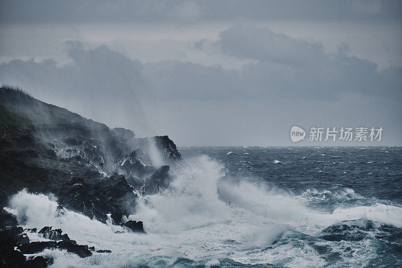 六月阴沉的一天，康沃尔纽基菲斯特拉海滩，海浪拍打着岩石。