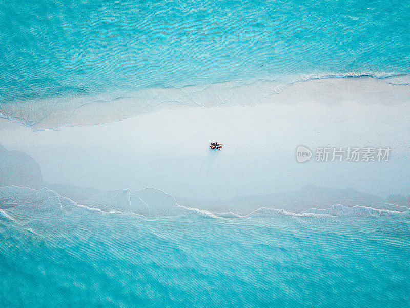 一对年轻的成年夫妇一起躺在马尔代夫碧绿的沙滩上