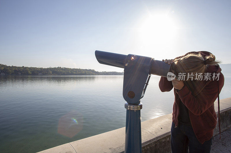 年轻人在阳光下用视野镜俯瞰湖面