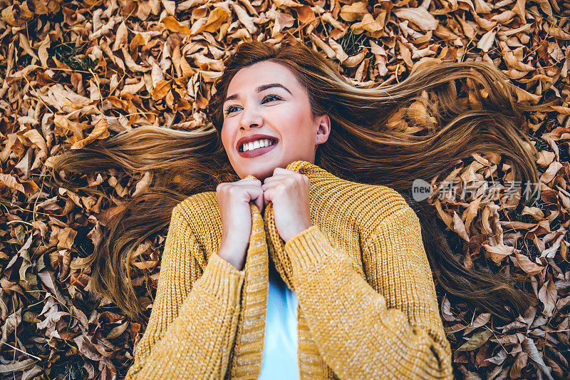 微笑的女人躺在秋叶上