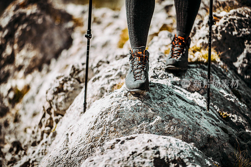 穿着登山靴，用手杖小心地在岩石地形上行走