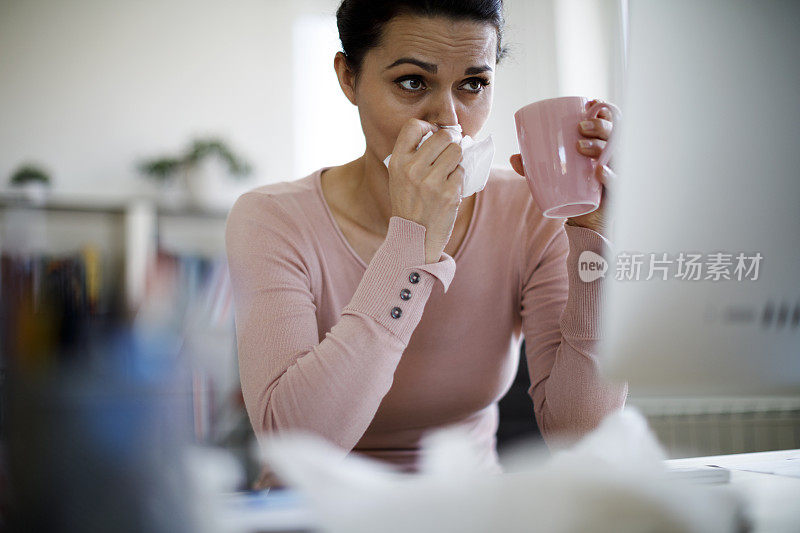 生病的女人一边工作一边喝热饮