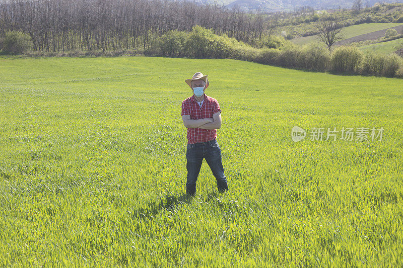 成年男性农民在农田上戴上防护口罩，以防止病毒感染