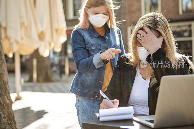 年轻的女学生戴着口罩和她的职业母亲