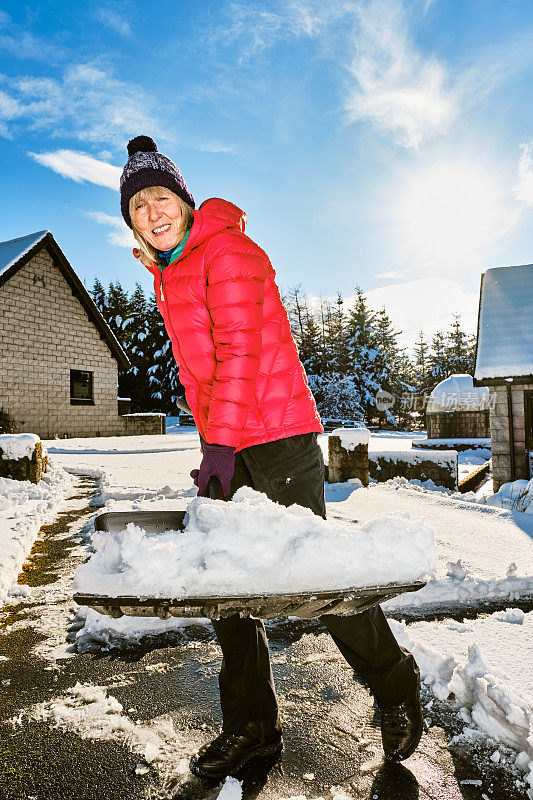 老妇人正在用雪铲清理前院的积雪