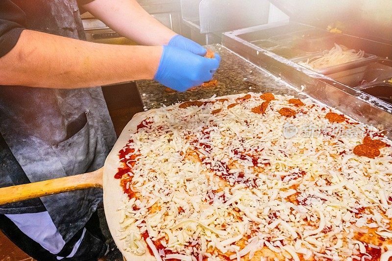 纽约的Pizzaiolo正在准备一个巨大的意大利辣香肠奶酪披萨外卖