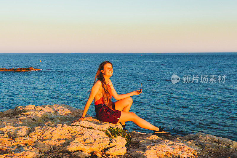 在法国南部的海岸上，一位年轻的女子与灿烂的夏日落日相遇